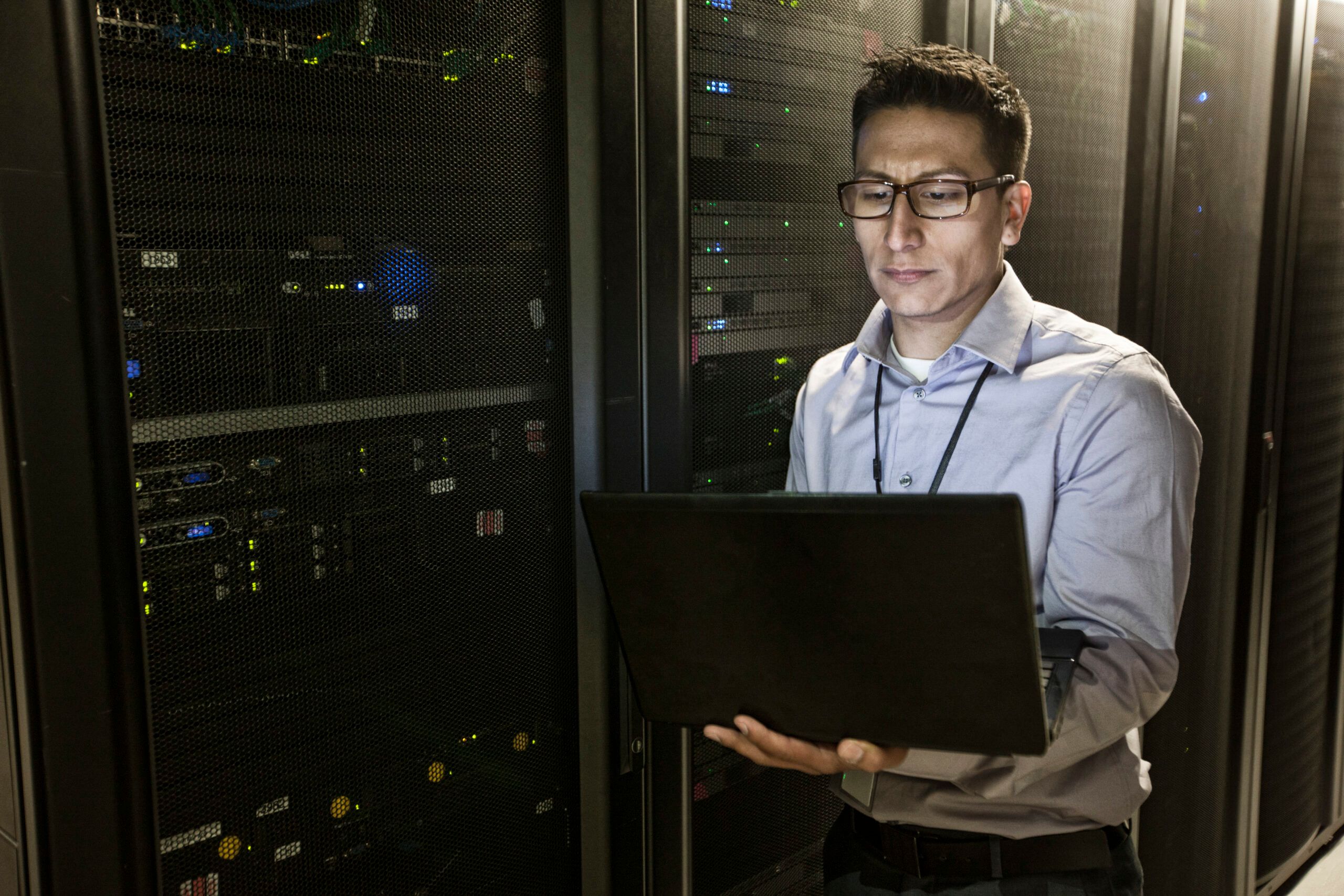 Professionnel IT effectuant la Gestion du patching Linux dans un centre de données avec des baies de serveurs et des équipements réseau