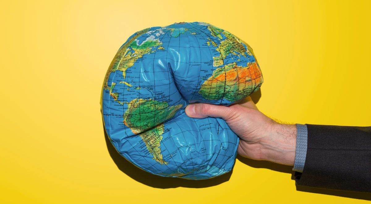 Main tenant le globe bleu et vert sur un fond jaune vif