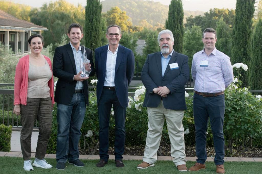 Photographie de cinq personnes lors d’un événement de remise de prix avec une toile de fond panoramique en plein air
