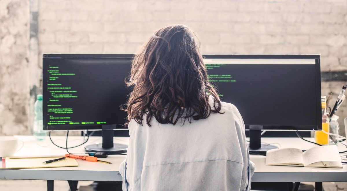 Personne travaillant à un bureau avec deux moniteurs affichant le code