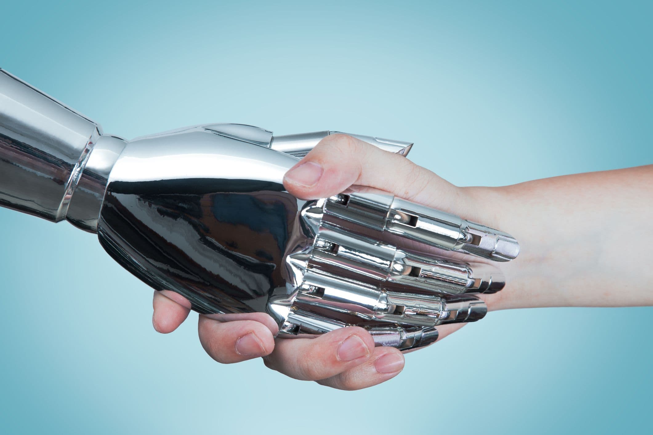 Une photo en gros plan d'une poignée de main entre un robot doté d'intelligence artificielle et un être humain.