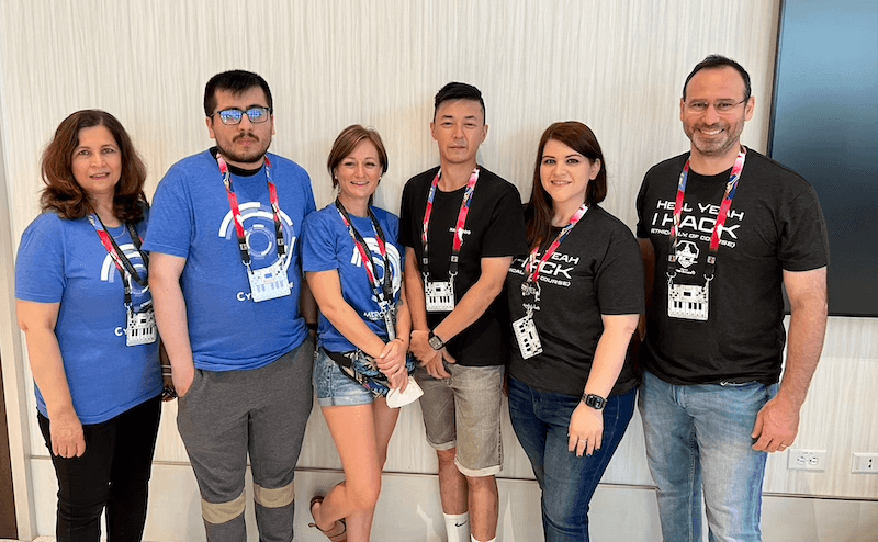 Photo de 6 personnes portant des t-shirts assortis et des longes de convention posant pour une photo dans une salle de convention.