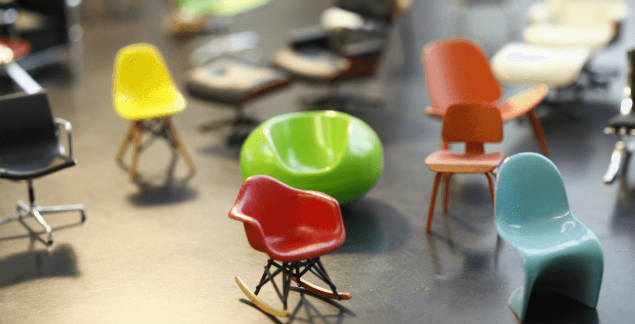 Une collection de chaises design miniatures aux formes élancées et aux couleurs vives.