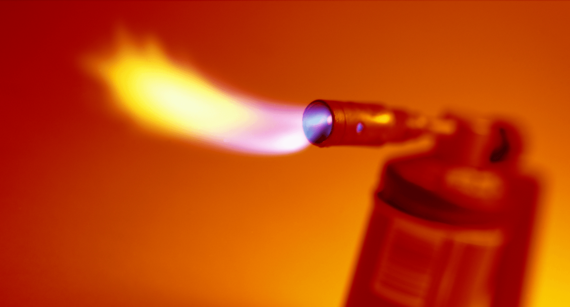 Une photo d'un chalumeau rouge crachant des flammes sur un fond orange.