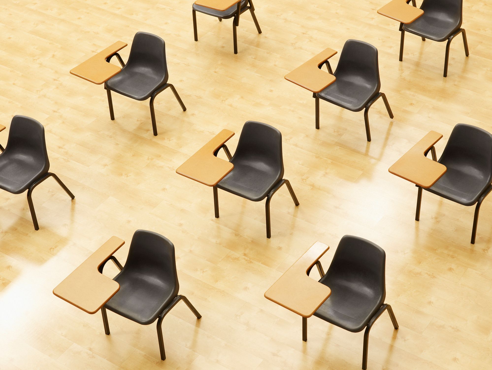 Des rangées de bureaux s'alignent en diagonale dans une salle de classe vide.