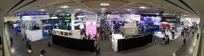 Vue aérienne de la salle des salons commerciaux avec plusieurs stands de fournisseurs et participants à la conférence