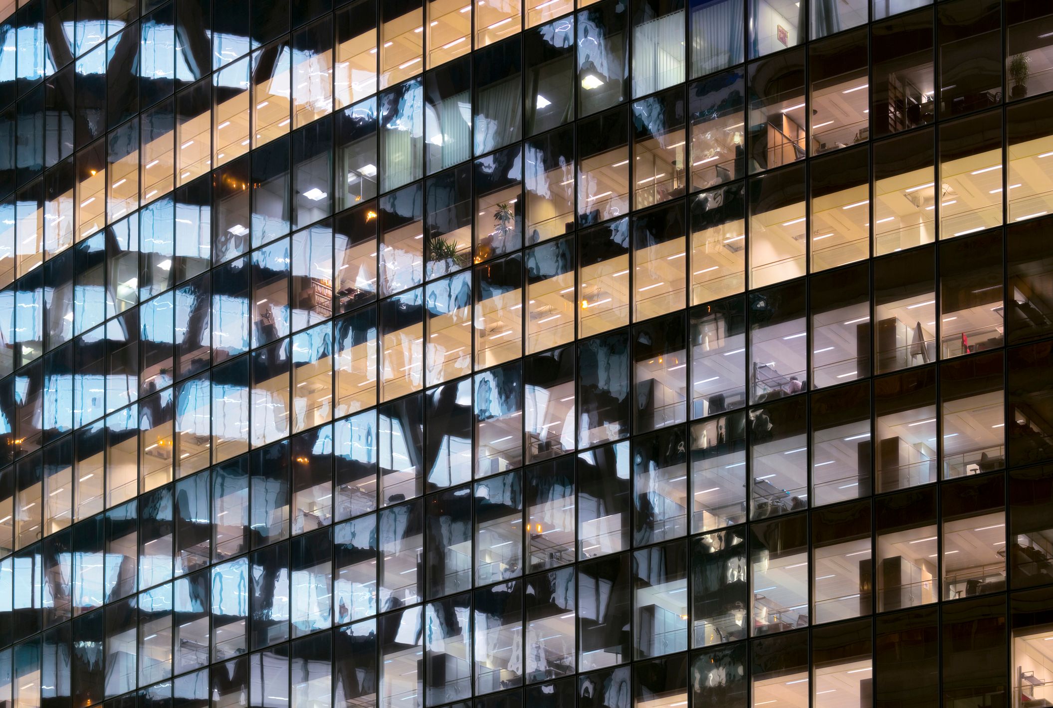 Photo de tours de bureaux en verre, avec des rangées de fenêtres se reflétant les unes dans les autres.