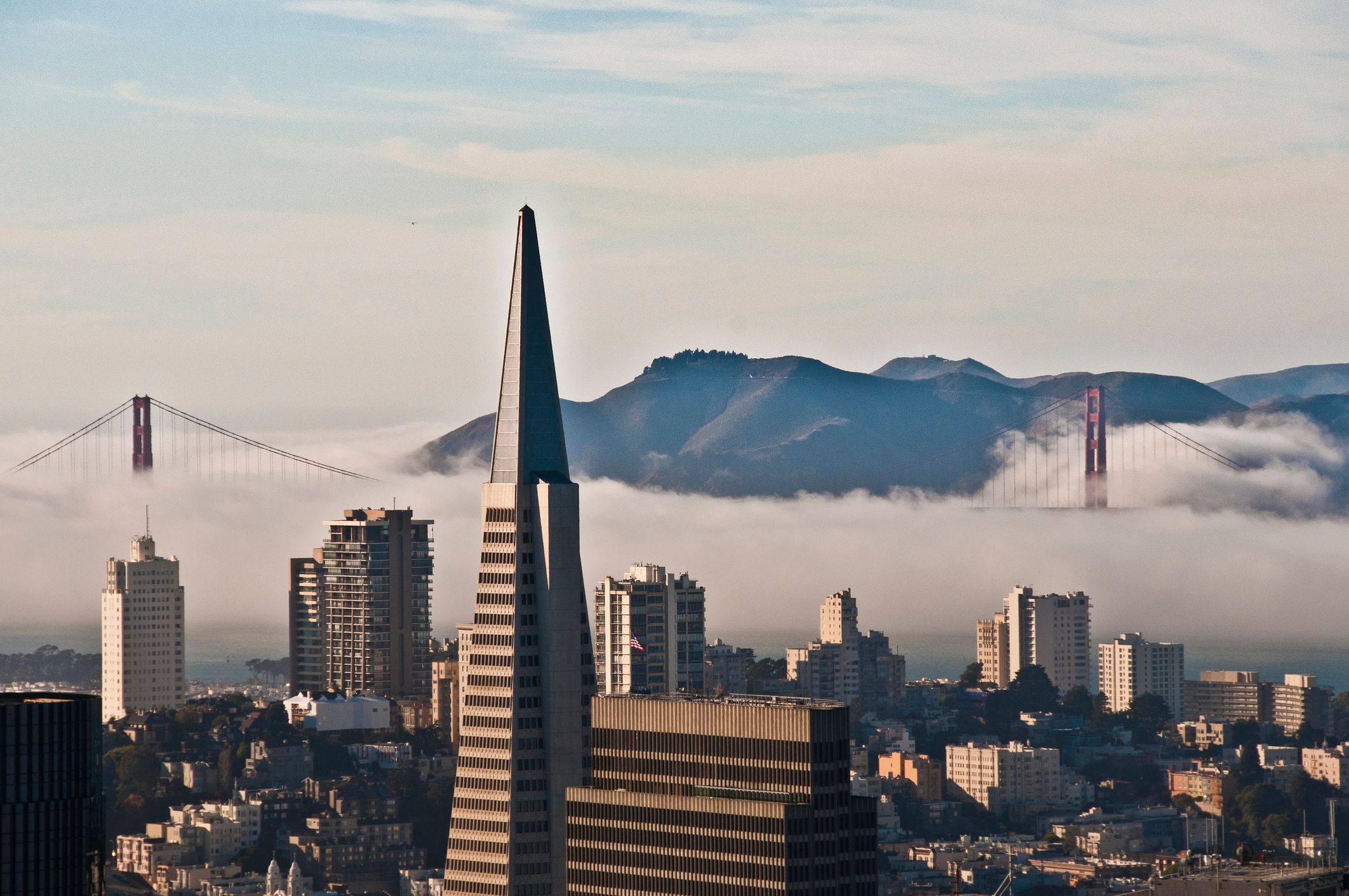 Une photo du panorama de San Francisco, avec la tour Transamerica Pyramid en gros plan et le Golden Gate Bridge qui émerge du brouillard en arrière-plan.