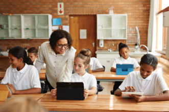Enseignant aidant les étudiants à leur bureau avec une tablette en classe