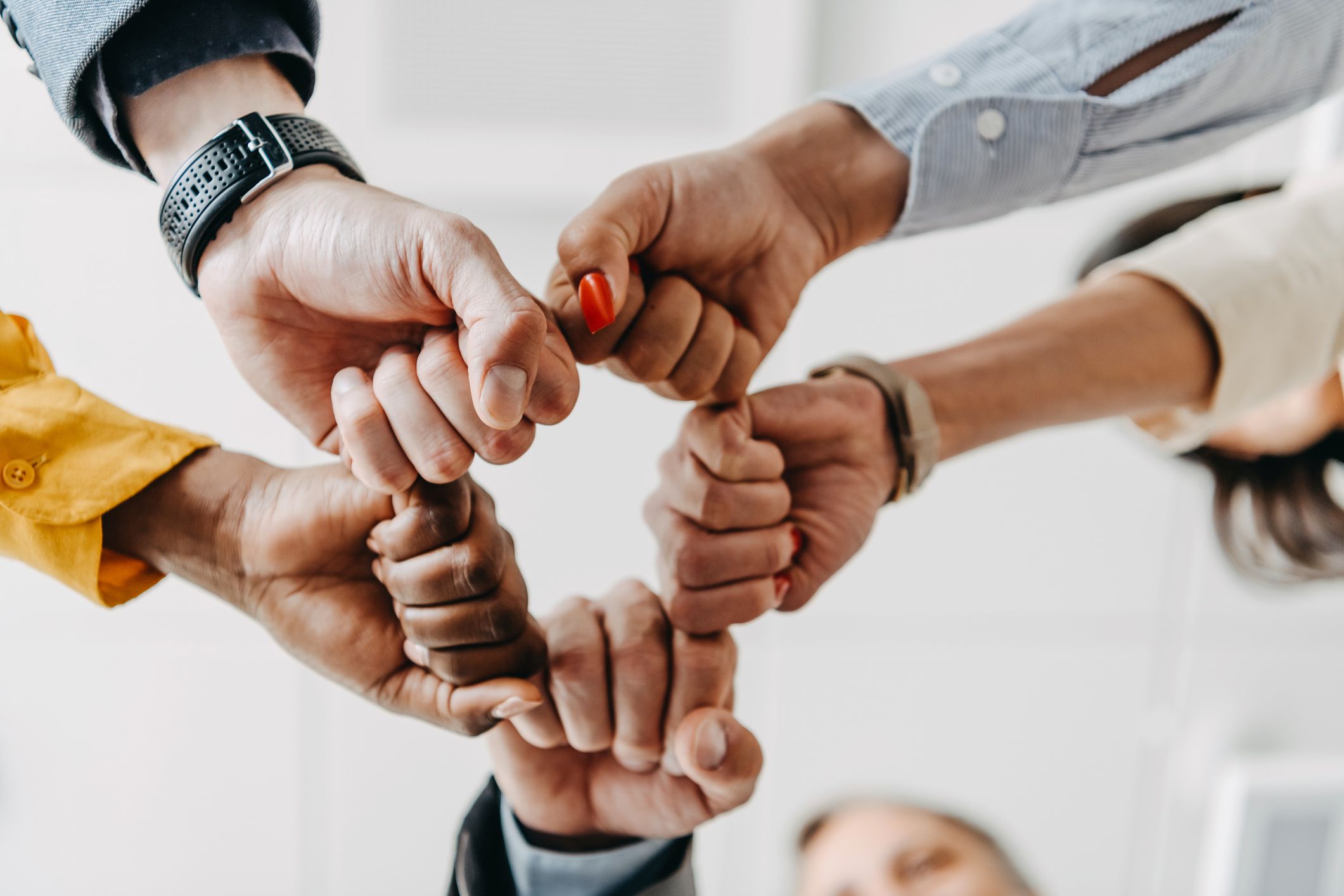 Un cluster de cinq employés de bureau multiethniques faisant un bump du poing en groupe