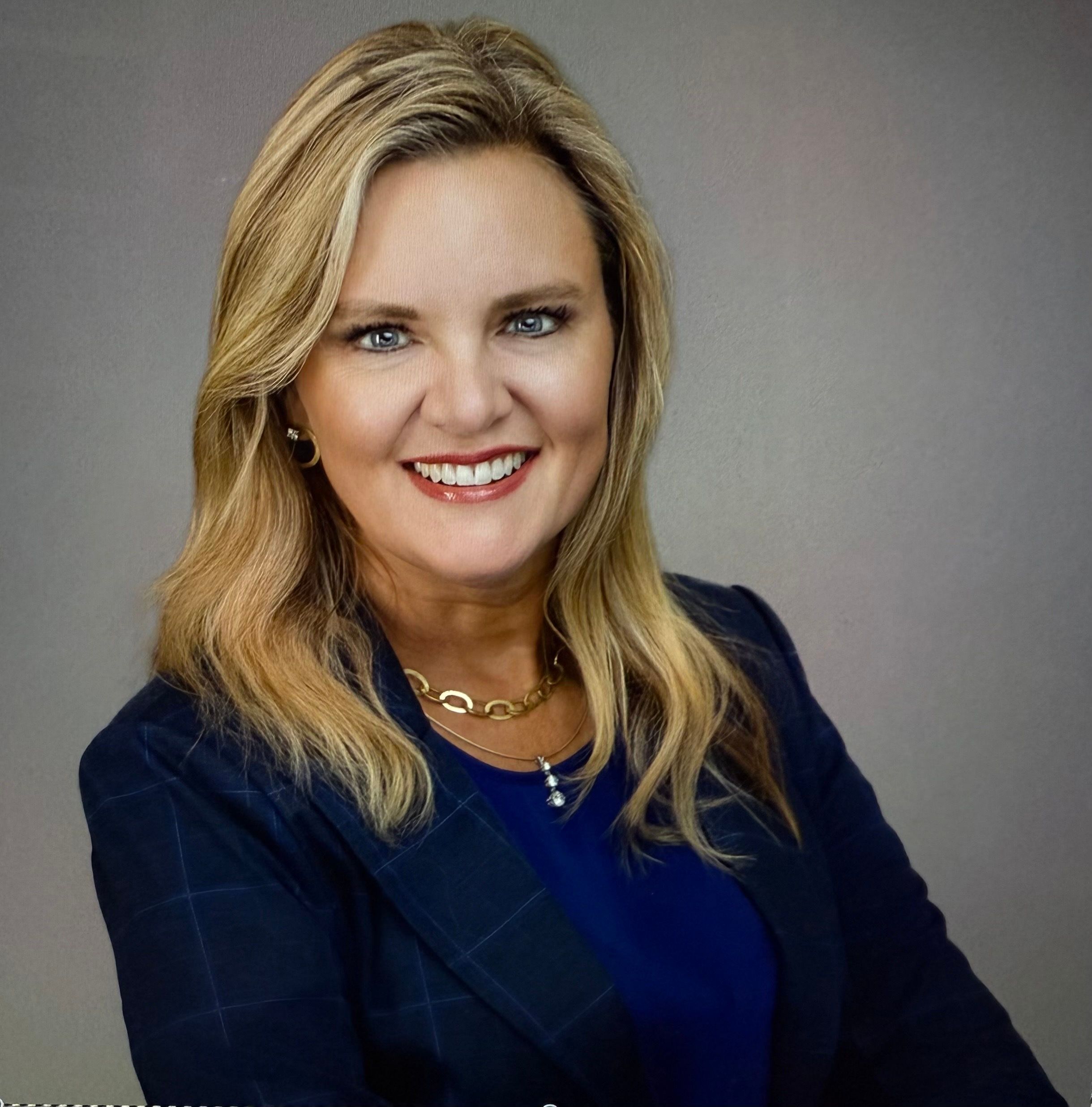 Portrait professionnel d’une femme aux cheveux blonds avec un blazer foncé