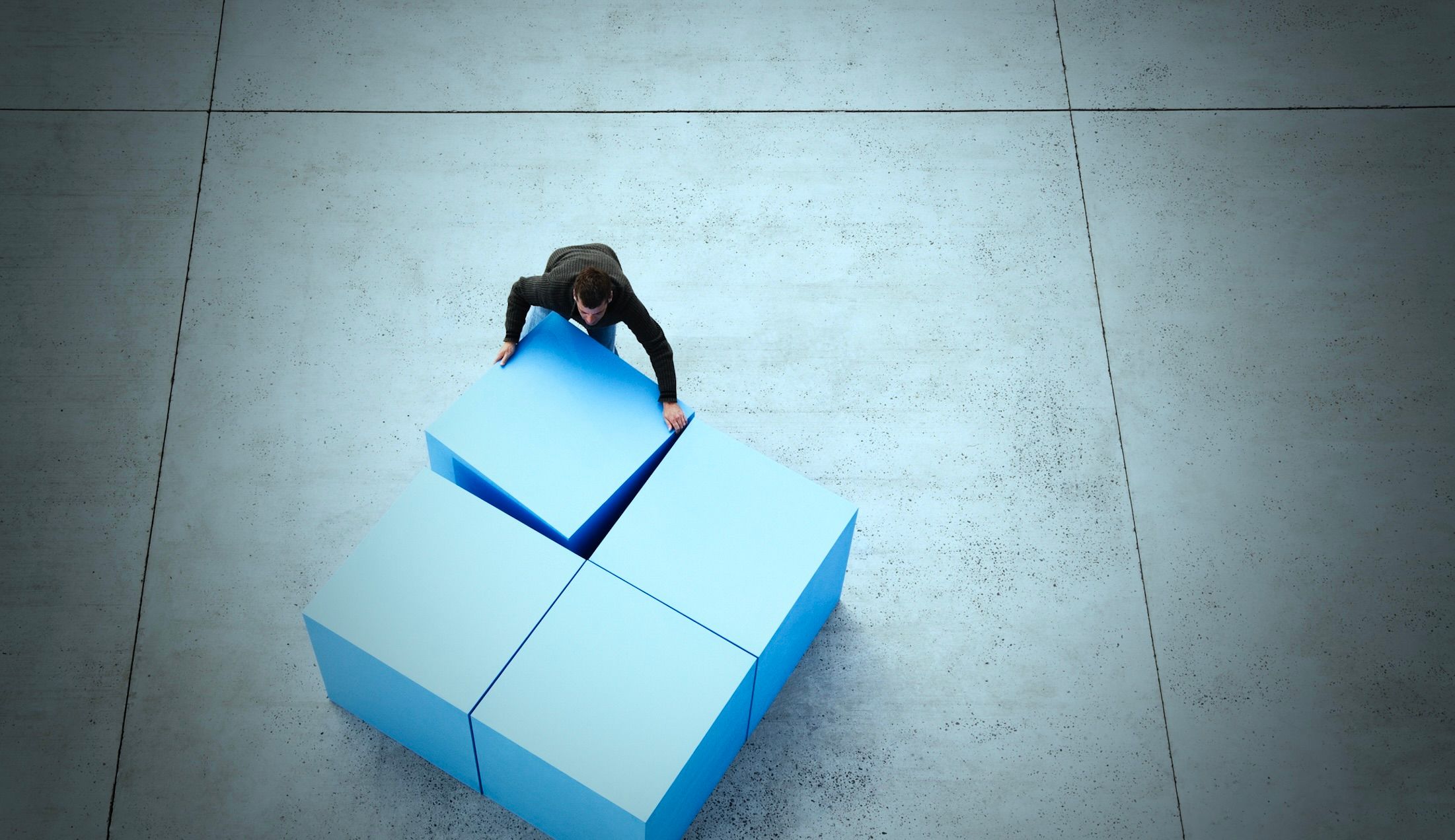 Photo d'un homme d'affaires, vu de dessus, qui assemble quatre cubes massifs