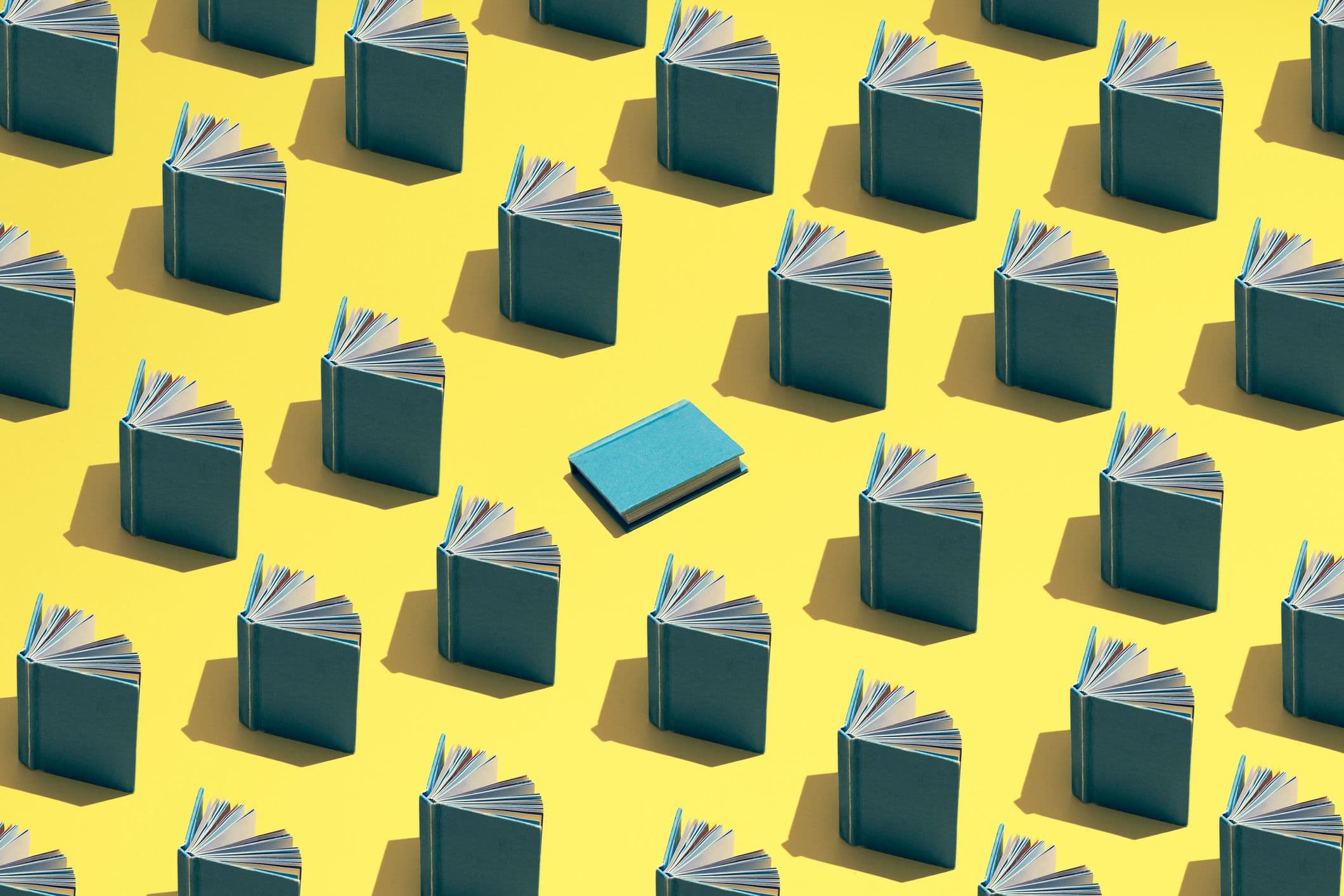 Image vedette du blog. Une illustration de livres ouverts disposés en rangées sur un fond jaune, avec un livre bleu au centre.